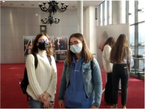 dwie dziewczyny stoją w holu teatralnym w maseczkach ochronnych na twarzy